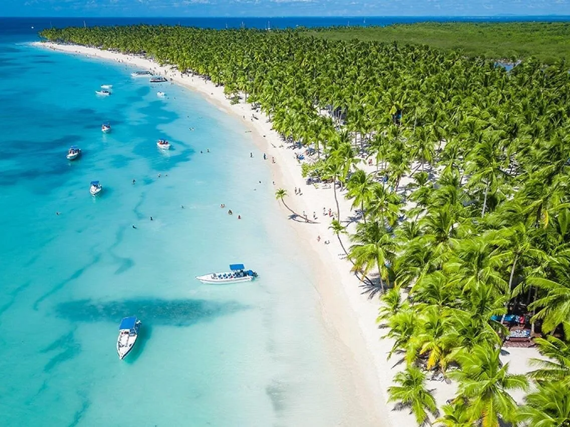 Vista aérea de una playa larga con barcos fondeados frente a la arena