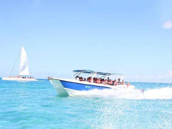 Ein Schnellboot fährt über türkises Wasser, dahinter ein Segelkatamaran